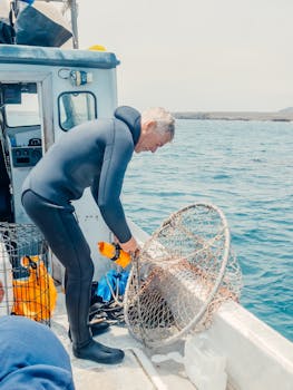 Fisherman in a wetsuit arranging nets on a boat in clear waters. Perfect for marine and fishing themes.