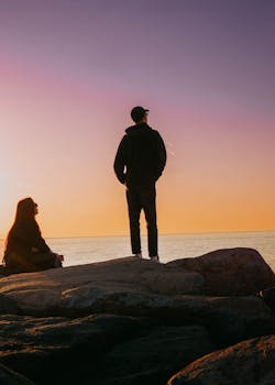 Two people enjoy a peaceful sunset on Batumi's rocky coast, embodying tranquility and connection.